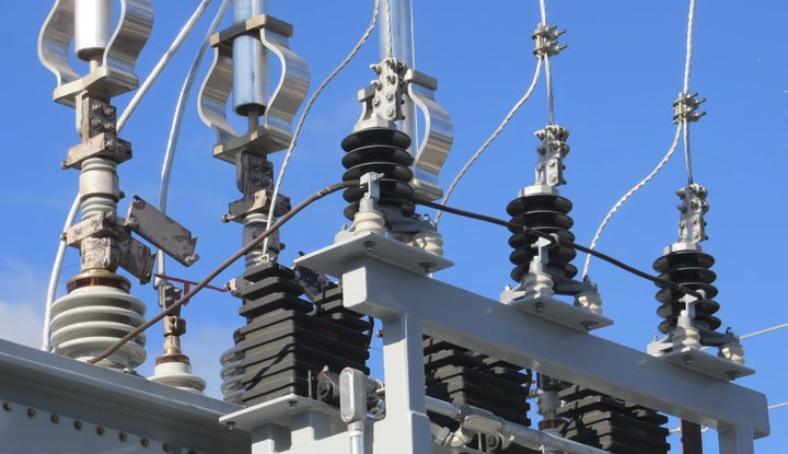 High-voltage transformer bushings against a blue sky